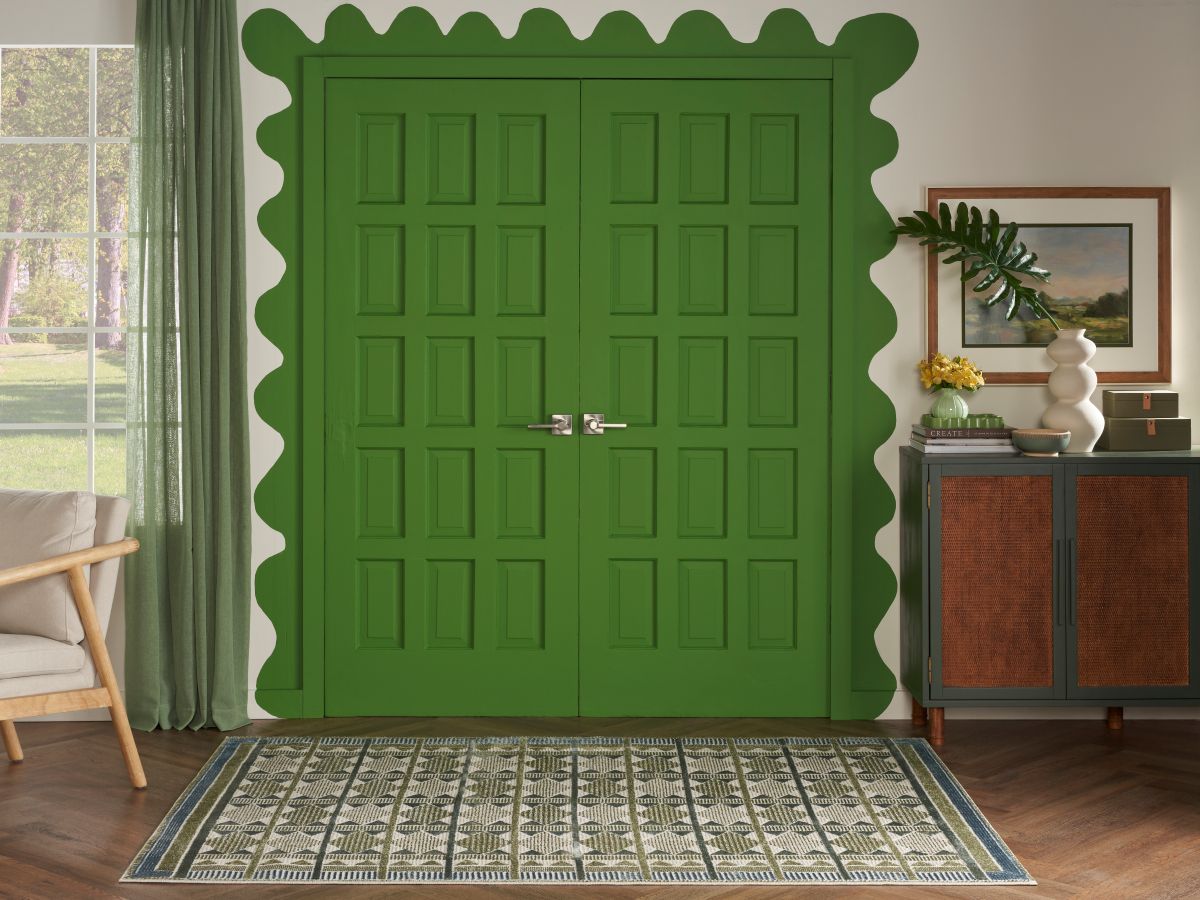 Pickle green front door with scalloped edges and a green rug in the entryway