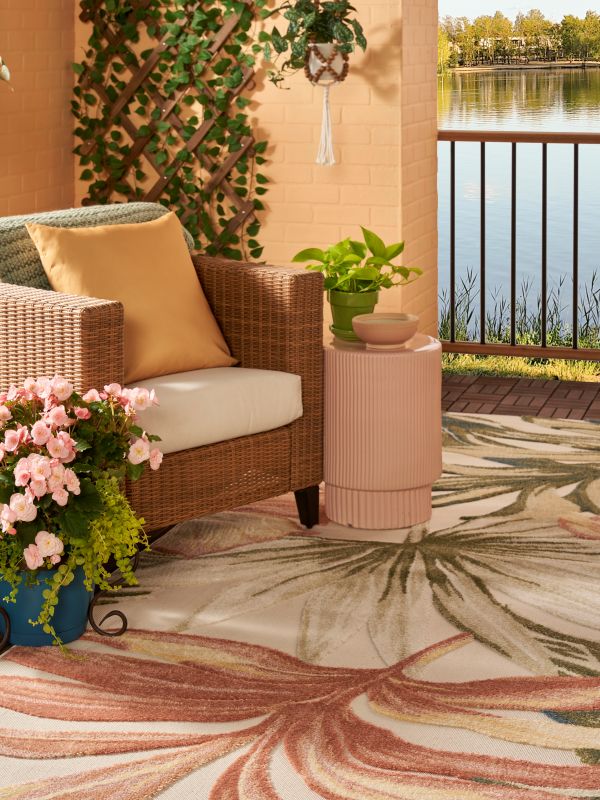 Corner view of a patio with a colorful tropical rug, plants, and a chair