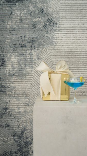 Cocktail on a plinth in front of an abstract blue and grey rug