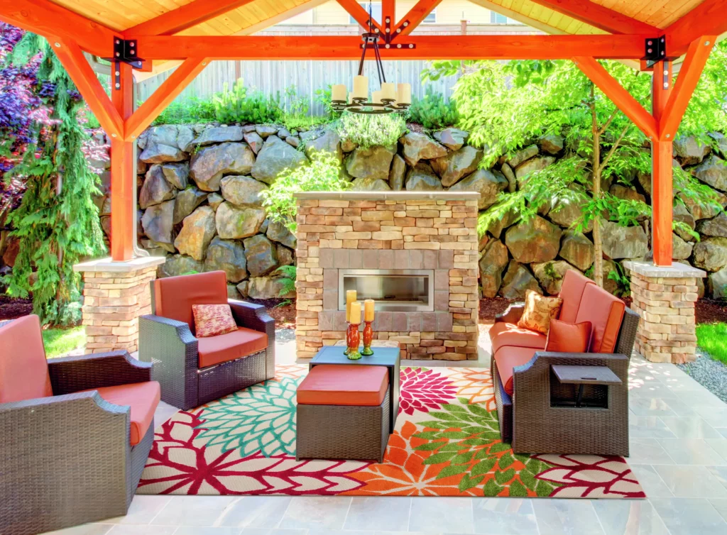 Nourison Aloha ALH05 green outdoor rug in a tropical al fresco dining setting with round tables and orange upholstered chairs on a wood deck