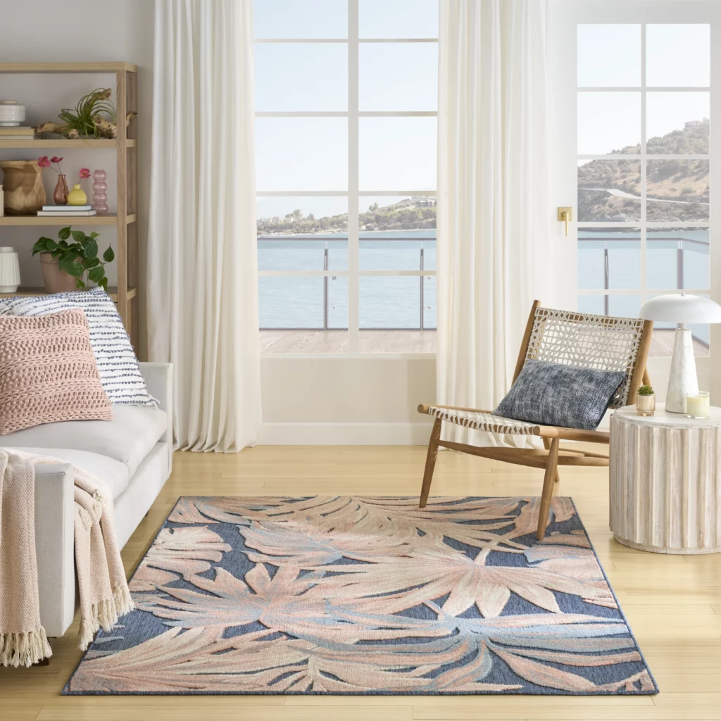 Aloha ALH43 blue rose indoor outdoor area rug with oversized botanical leaf pattern in a coastal living room with ocean view