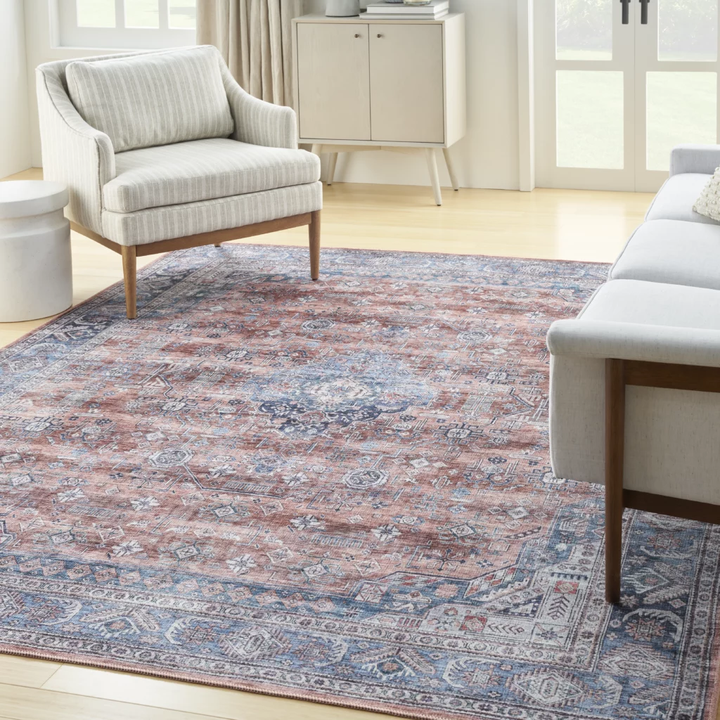 Nourison Grand Washables GRW01 Blue Multicolor 5x7 distressed Persian-style area rug on light hardwood floor in a bright living room with a striped accent chair and white cabinet