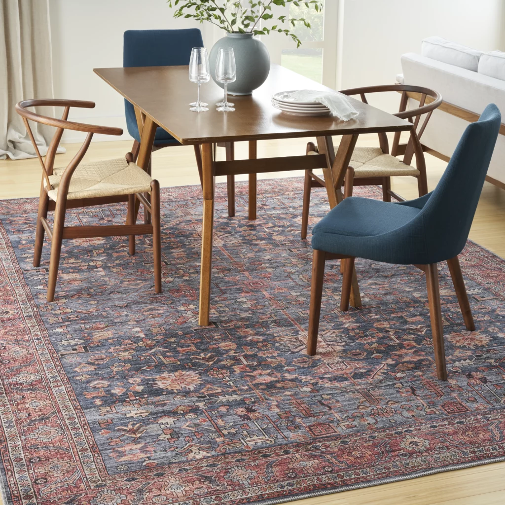 Nourison Grand Washables GRW02 Navy Brick 5x7 distressed Persian-style area rug under a walnut dining table with wishbone chairs and navy upholstered seating in a bright dining room