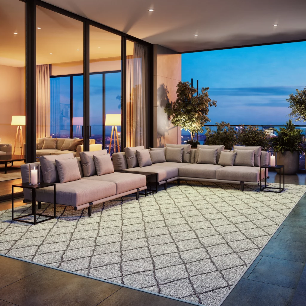 Nourison Seasons broadloom flatweave rug in a contemporary high-rise living space with floor-to-ceiling windows, a large sectional sofa, and candlelit side tables at dusk