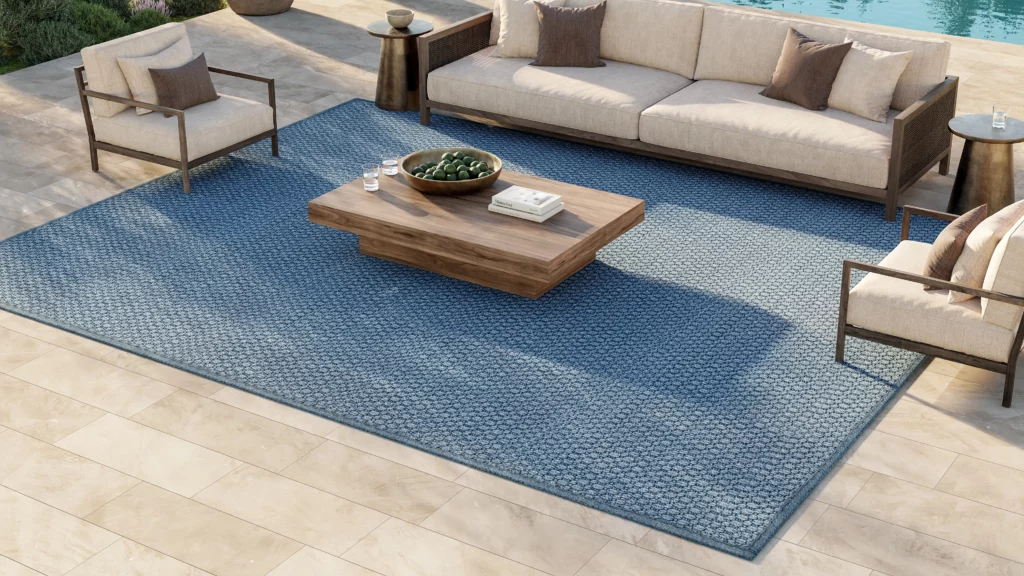 Nourison Wherever Sisal broadloom rug in sky blue under a full outdoor living room arrangement with a sectional sofa and wood coffee table beside a pool