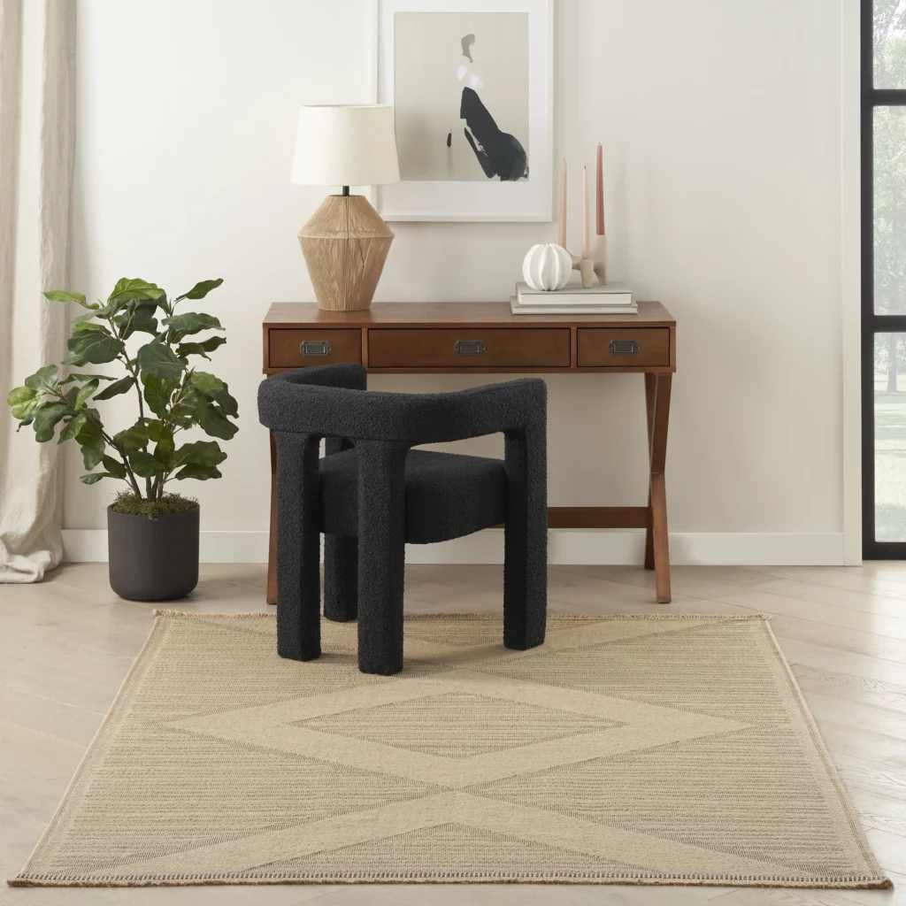 Nourison Washable Jute WSJ01 Natural Beige 5x7 area rug with a tonal diamond geometric pattern under a black bouclé chair and walnut desk in a minimal, neutral home office