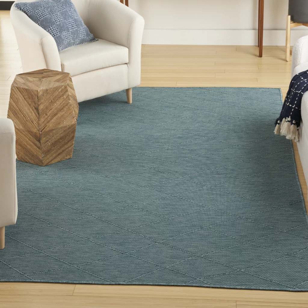 Nourison Washable Solutions WSL01 Aqua 5x7 area rug with a tonal diamond lattice pattern on light hardwood floors in a casual living room with a cream armchair and geometric wood side table