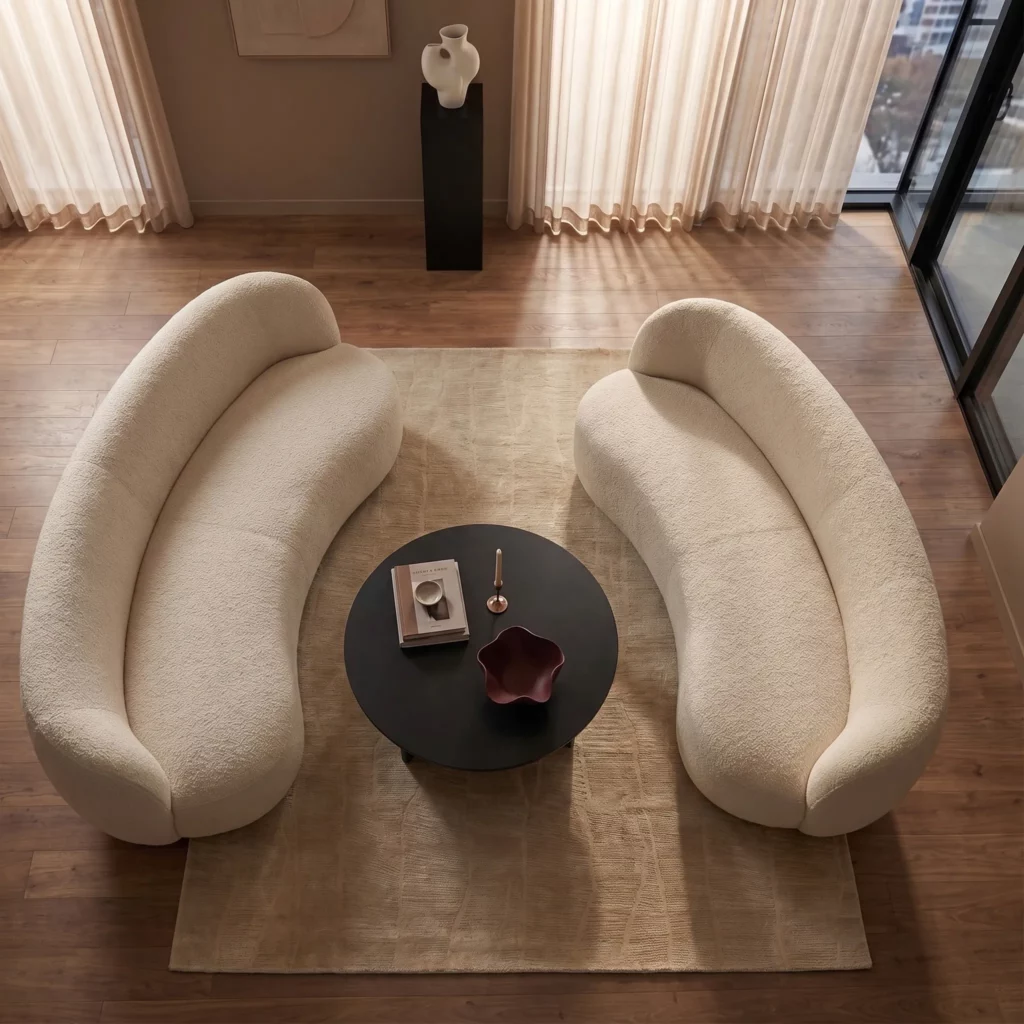 Taupe hand-loomed silk rug with a subtle tonal pattern, seen from above between two curved cream bouclé sofas and a round black coffee table